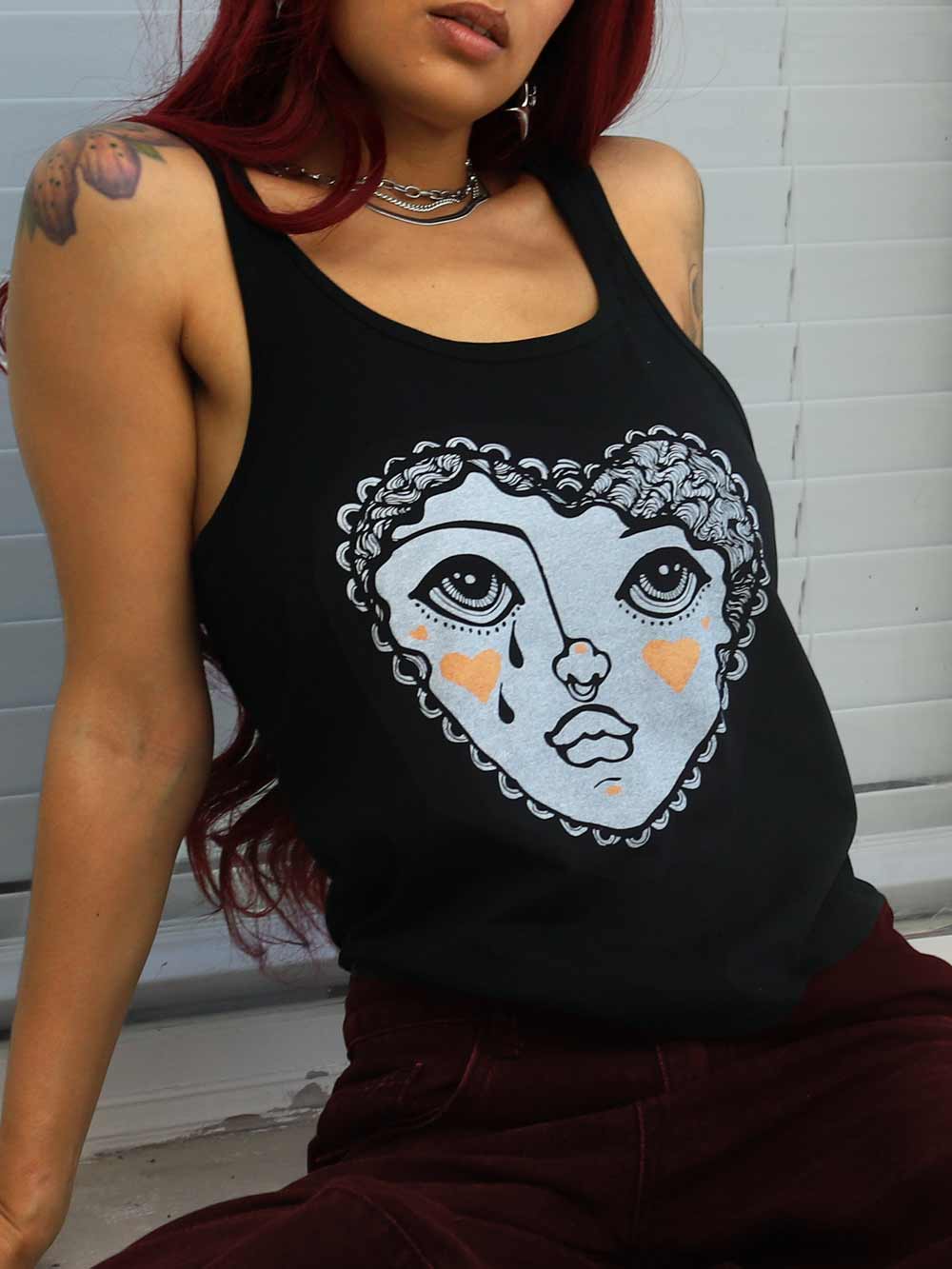 Person wearing a black tank top with a graphic design of a face in a heart shape.