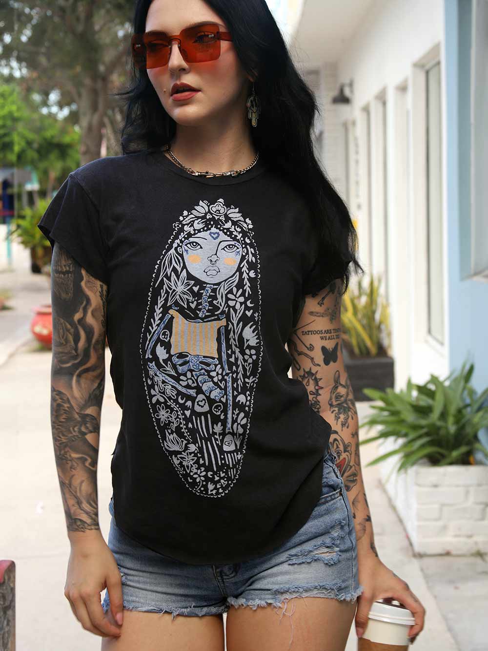 Person wearing a black t-shirt with a graphic design, standing outdoors.