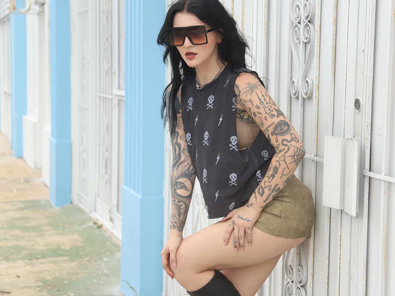 Black crop top with skull and lightning bolt pattern, standing against a white wall.