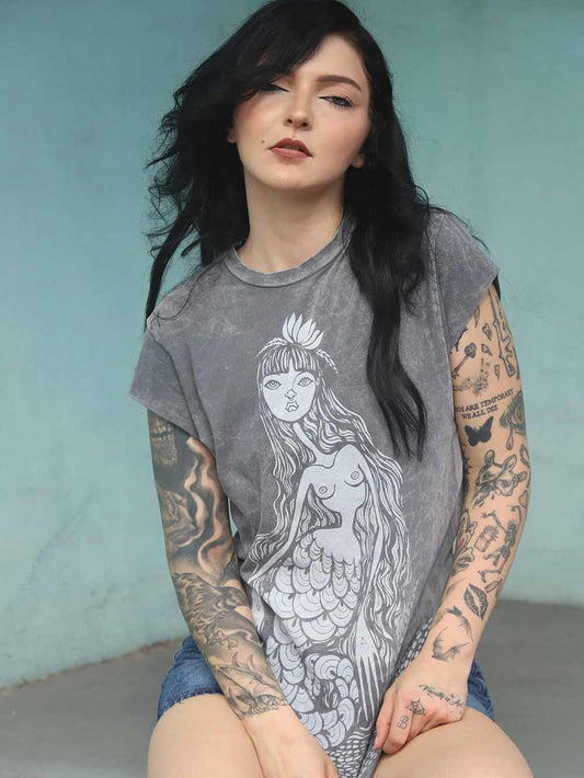 Woman wearing a sleeveless gray t-shirt with a mermaid design against a light blue background