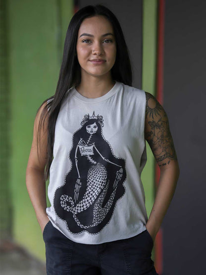 A woman wearing a white crop with a black graphic of a mermaid skeleton