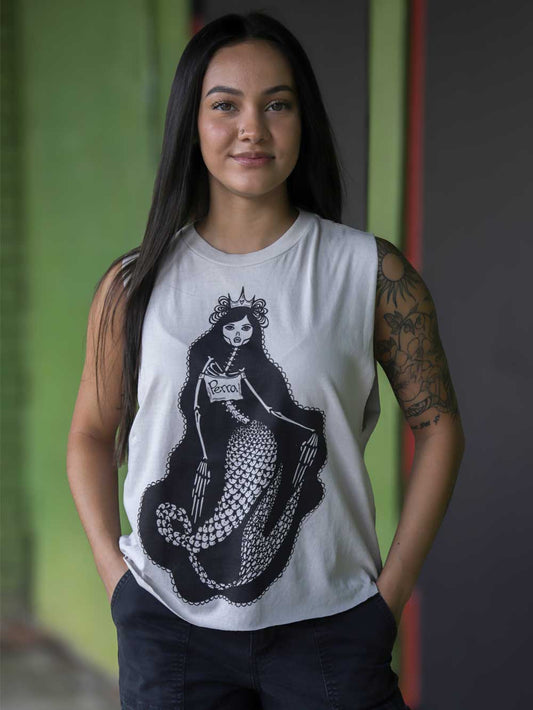 A woman wearing a white crop with a black graphic of a mermaid skeleton