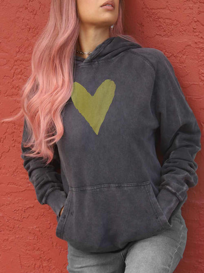 Woman wearing a vintage black hoodie with a gold heart design against a red wall