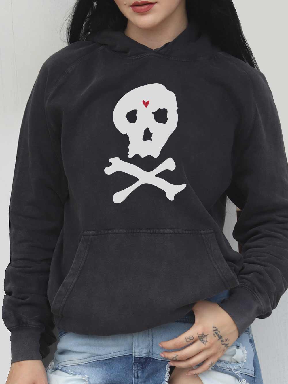 Black hoodie with skull and crossbones design worn by a woman against a plain background