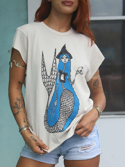 Woman wearing a white t-shirt with a blue and black mermaid design.