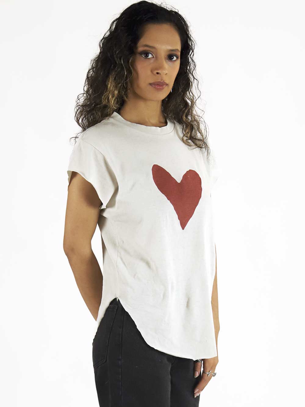 Woman wearing a white t-shirt with a red heart design on a plain background