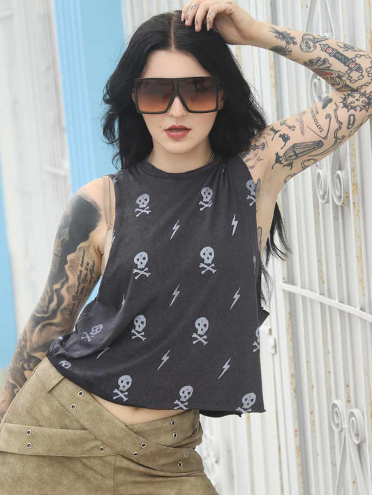Rocker Woman wearing a black crop top with skull and lightning bolt patterns, standing against a white building.