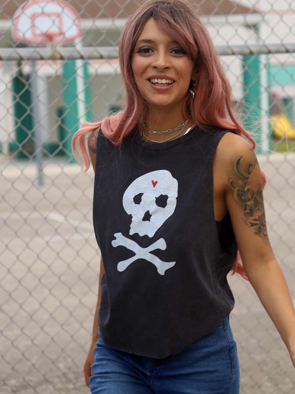 Woman wearing a black sleeveless shirt with a skull design near basketball court.