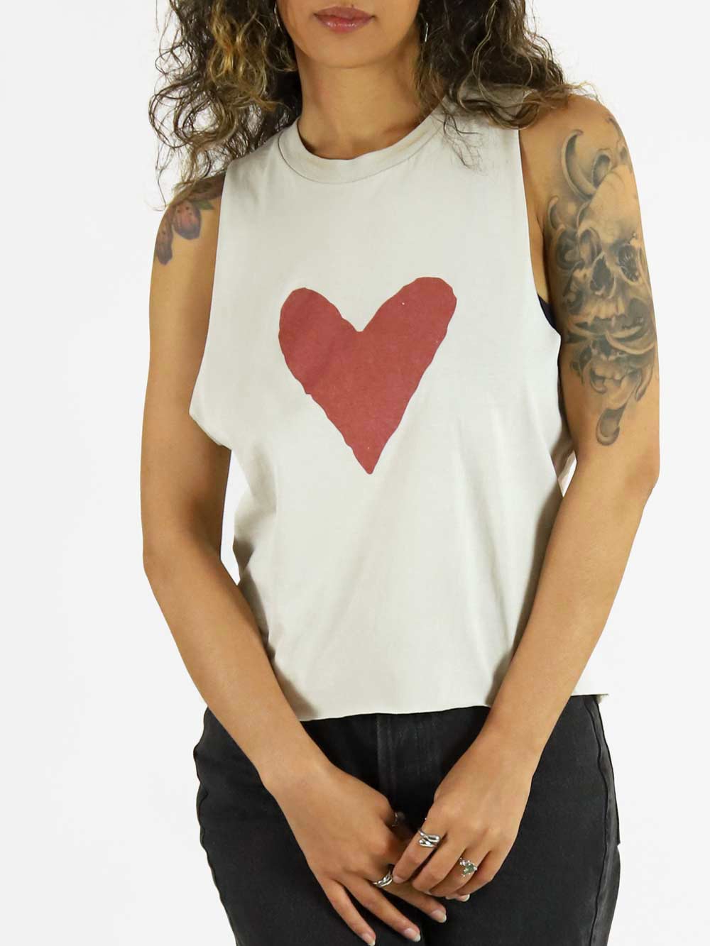 Model wearing a white sleeveless top with a red heart design on a plain background