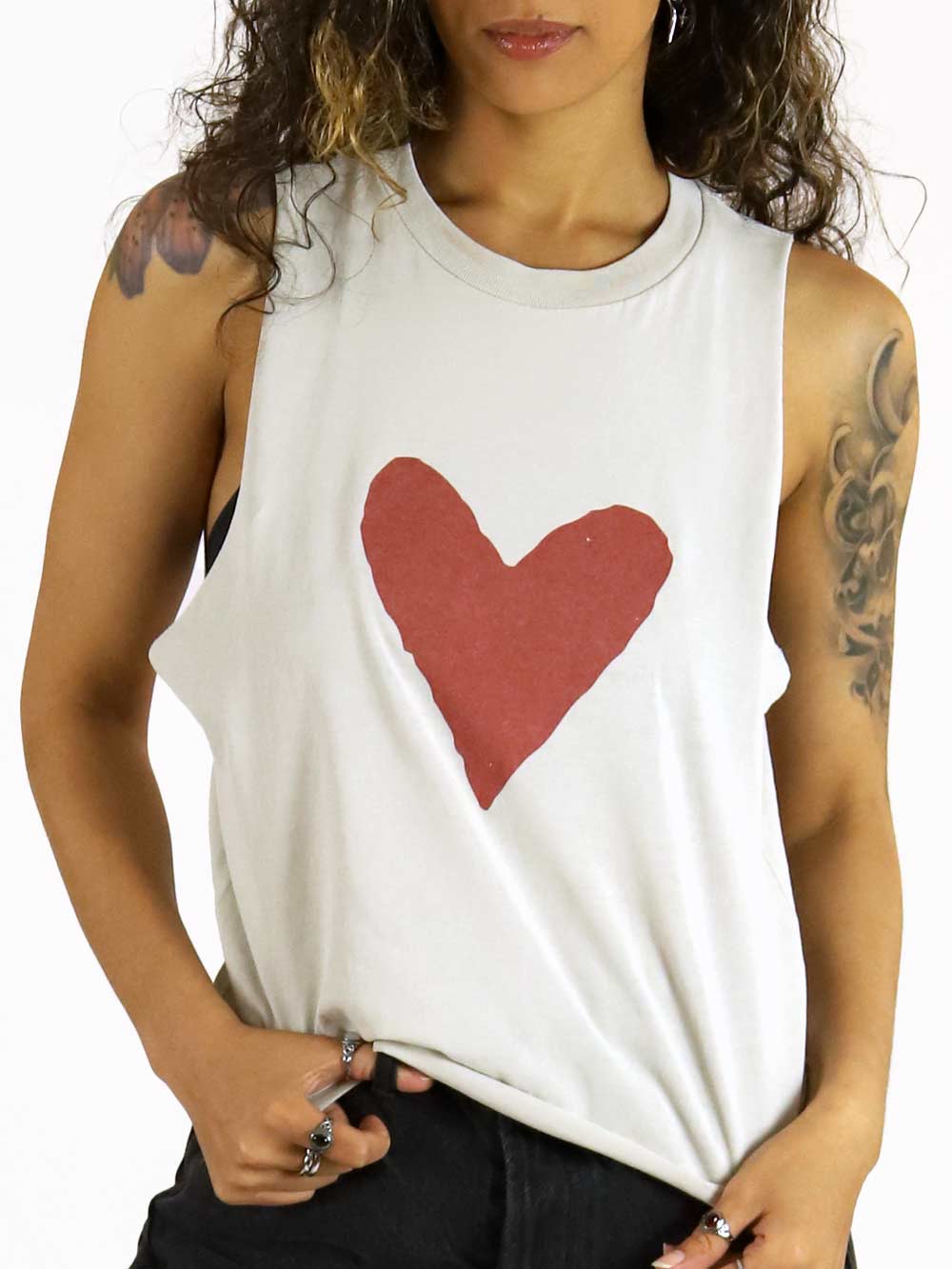 Woman wearing a white sleeveless shirt with a red heart design. 