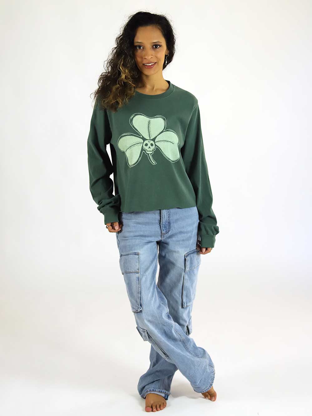 Woman wearing a green long sleeve crop with a shamrock design on a white background