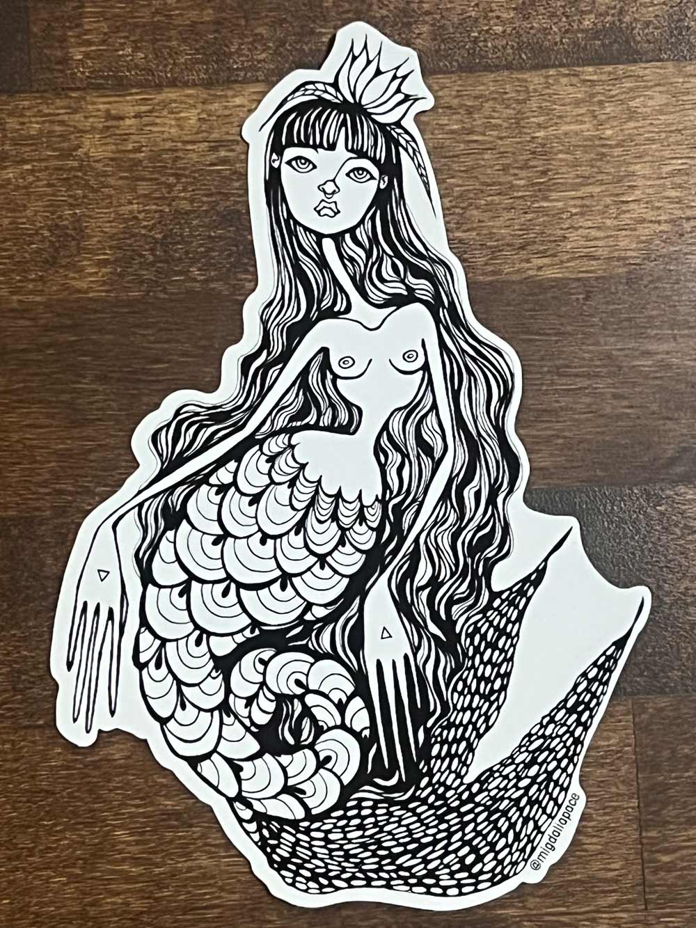 Black and white mermaid sticker on a wooden surface