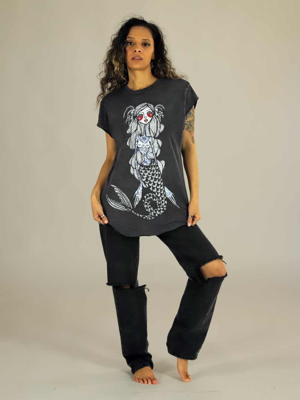 Woman wearing a black t-shirt with a mermaid graphic design on a plain background
