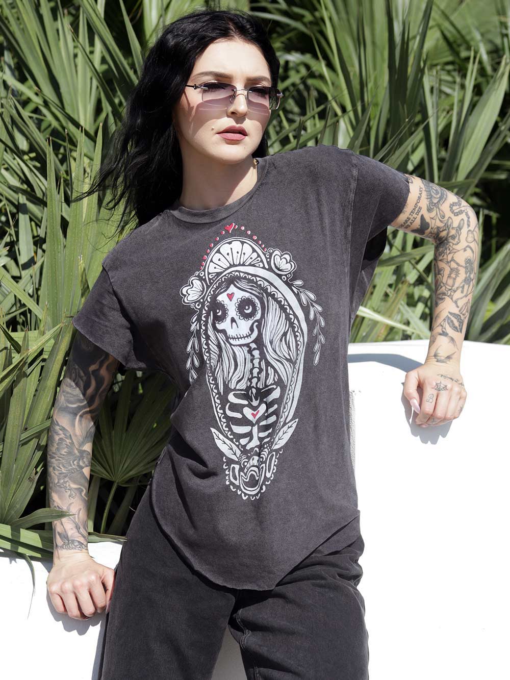 Woman wearing a dark gray t-shirt with a Skeleton Madonna design outdoors.