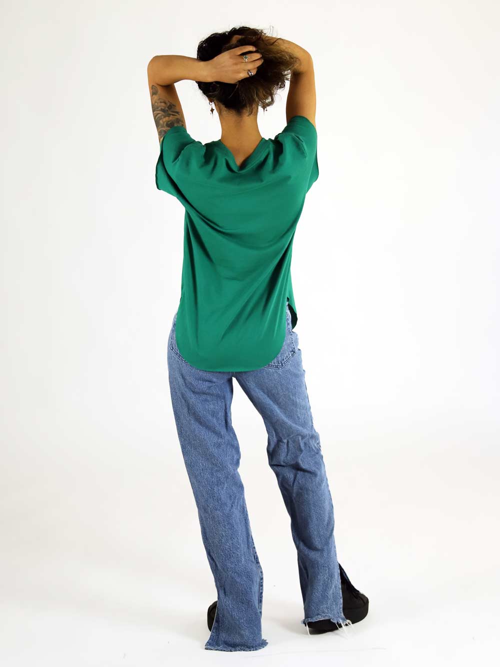 Woman wearing a green shirt and blue jeans on a white background