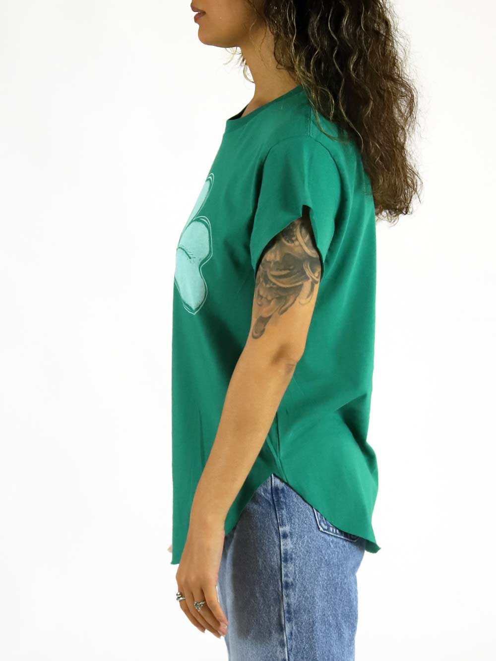 Woman wearing a green t-shirt with a clover, standing profile on a white background