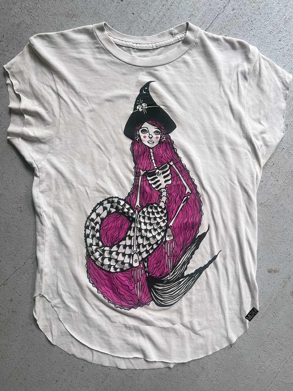 White t-shirt with a graphic of a mermaid witch with purple hair.